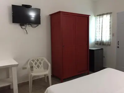 a bedroom with a red cabinet and a white chair at Albergo El Pulpo, Bayahíbe in Bayahibe