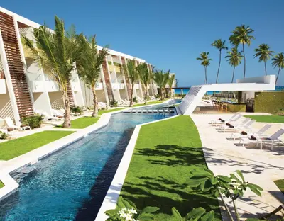 a pool at the resort with chairs and palm trees at Dreams Onyx Resort & Spa - All Inclusive in Punta Cana