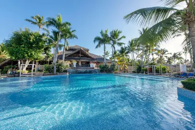 a swimming pool at a resort with palm trees at Viva Dominicus Beach by Wyndham, A Trademark All Inclusive in Bayahibe