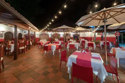 a restaurant with white tables and red chairs and umbrellas at Viva Dominicus Beach by Wyndham, A Trademark All Inclusive in Bayahibe