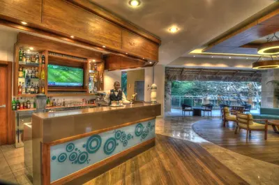 a bar in a restaurant with a person standing behind the counter at Viva Dominicus Palace by Wyndham, A Trademark All Inclusive in Bayahibe