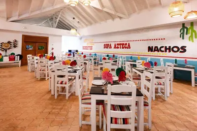 a dining room with white tables and white chairs at Viva Tangerine by Wyndham, A Trademark All Inclusive in Cabarete
