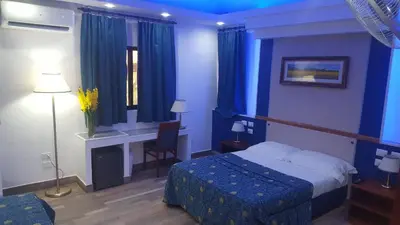 a hotel room with a bed and a desk and blue curtains at Hotel El Dorado in La Romana