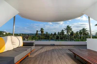 a living room with a couch and a balcony with palm trees at Puerto Plaza Las Terrenas in Las Terrenas