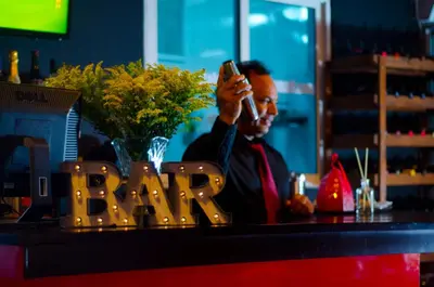 a man talking on a cell phone at a bar at Hotel Casa Jum in Santiago de los Caballeros