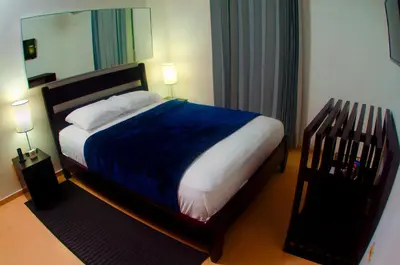 a bedroom with a bed with a blue blanket and a mirror at Hotel Casa Jum in Santiago de los Caballeros