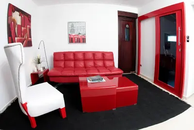 a red couch and a chair in a room at Hotel Casa Jum in Santiago de los Caballeros