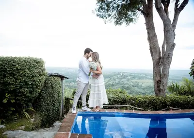 a bride and groom kissing next to a swimming pool at Ecolodge Tubagua Puerto Plata in Tubagua