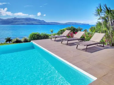a pool with chairs and the ocean in the background at Villa Salamandra in Las Galeras