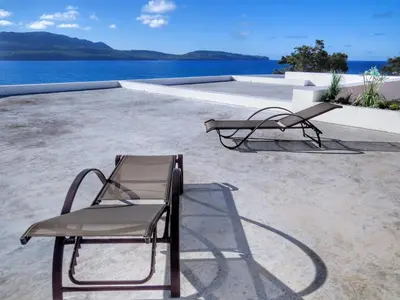 a pair of chairs sitting on a patio next to the water at Villa Salamandra in Las Galeras