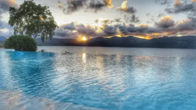 a large body of water with a tree and the sunset at Villa Salamandra in Las Galeras