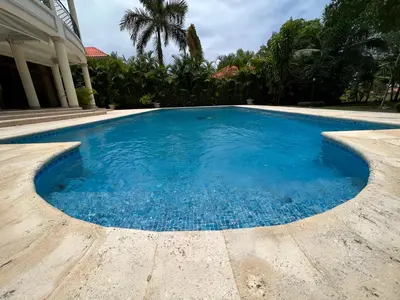 a swimming pool with blue water in front of a house at Villamorametro in Juan Dolio