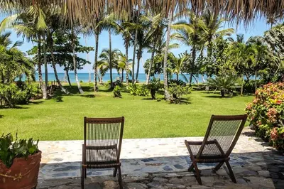 two chairs in a park with palm trees and the ocean at Jasmine La Playita - Ocean Front in Las Galeras