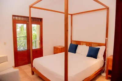 a bedroom with a four poster bed with blue pillows at Villa Diana in Las Galeras