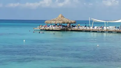 a pier with chairs and a straw umbrella on the water at Appartamento Vista Mare in Bayahibe
