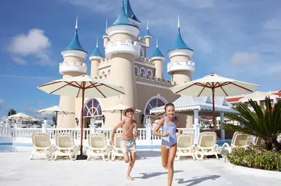two children walking in front of the disney castle at Bahia Principe Fantasia Punta Cana - All Inclusive in Punta Cana