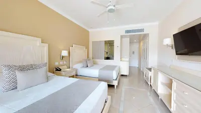 a bedroom with two beds and a flat screen tv at Bahia Principe Fantasia Punta Cana - All Inclusive in Punta Cana