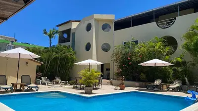 a pool in front of a building with umbrellas at Hotel Don Andres in Sosúa