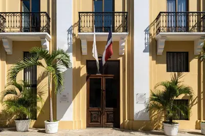a building with a door with a flag and palm trees at Gran Hotel Europa Santo Domingo Trademark Collection by Wyndham in Santo Domingo