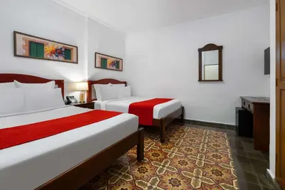 a hotel room with two beds and a mirror at Gran Hotel Europa Santo Domingo Trademark Collection by Wyndham in Santo Domingo