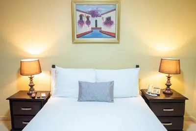 a bedroom with a white bed with two nightstands and two lamps at Hotel Real Bella Vista in Santo Domingo