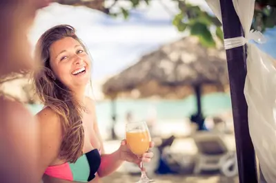a woman in a bikini holding a glass of orange juice at BlueBay Villas Doradas Adults Only-All Inclusive in San Felipe de Puerto Plata