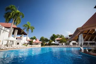 a swimming pool at a resort with chairs and palm trees at BlueBay Villas Doradas Adults Only-All Inclusive in San Felipe de Puerto Plata