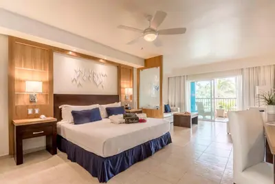 a bedroom with a large bed with a ceiling fan at Ocean Blue & Sand Beach Resort - All Inclusive in Punta Cana