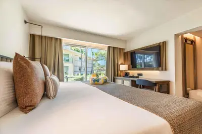 a bedroom with a large bed with a desk and a window at Grand Palladium Select Bávaro - All Inclusive in Punta Cana