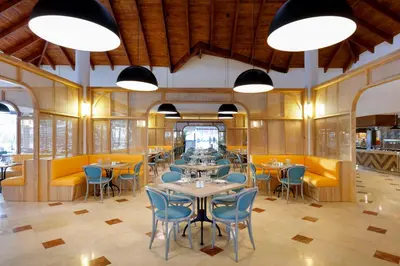 a restaurant with tables and chairs and yellow booths at Grand Palladium Punta Cana Resort & Spa - All Inclusive in Punta Cana