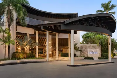 a large building with a black roof and palm trees at Grand Palladium Punta Cana Resort & Spa - All Inclusive in Punta Cana