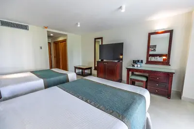 a hotel room with two beds and a television at Dominican Fiesta Hotel in Santo Domingo