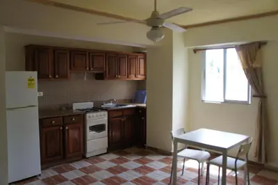 a kitchen with wooden cabinets and a table and a white refrigerator at Plaza Real Resort in Juan Dolio