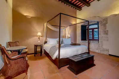 a bedroom with a canopy bed and a chair at Hodelpa Nicolás de Ovando in Santo Domingo