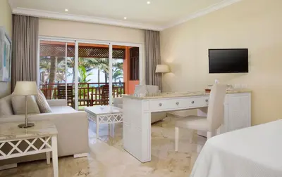 a hotel room with a desk and a bed and a television at VIK hotel Arena Blanca in Punta Cana