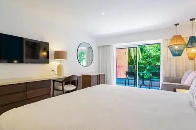 a hotel room with a bed and a desk and a window at Caribe Deluxe Princess - All Inclusive in Punta Cana