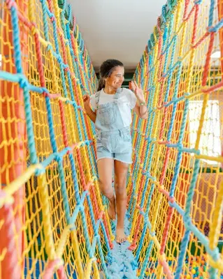a woman is walking on a rope bridge at Hard Rock Hotel & Casino Punta Cana - All Inclusive in Punta Cana