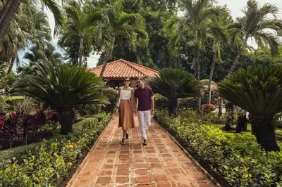 a man and a woman walking down a path in a garden at El Embajador, a Royal Hideaway Hotel in Santo Domingo