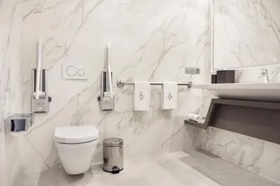 a white bathroom with a toilet and a sink at El Embajador, a Royal Hideaway Hotel in Santo Domingo