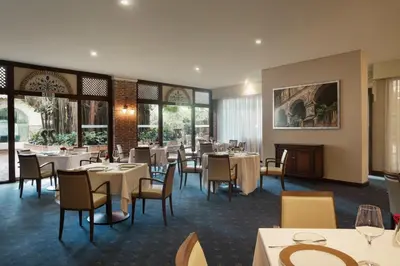 a dining room with tables and chairs and windows at El Embajador, a Royal Hideaway Hotel in Santo Domingo