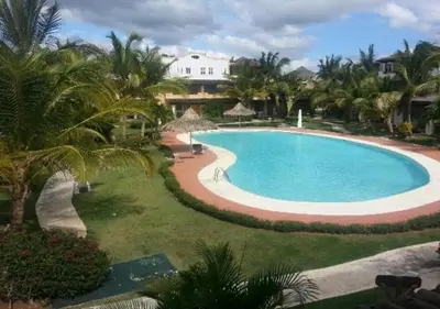 a large swimming pool with palm trees and a building at Tamarindo in Bayahibe