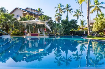 a swimming pool in front of a house with palm trees at Hotel Alisei in Las Terrenas