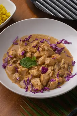 a white plate of food with chicken and purple cabbage at El Encuentro Surf Lodge in Cabarete