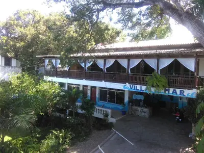 a large house with a balcony and a tree at Villa Mar Sosua in Sosúa