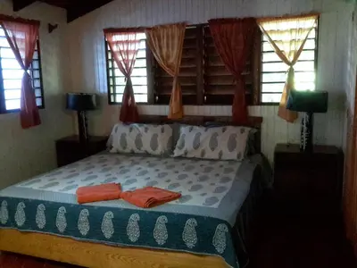 a bedroom with a bed with two pillows and windows at Villa Mar Sosua in Sosúa