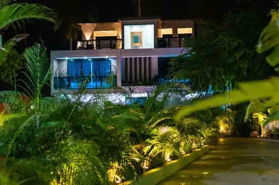 a house lit up at night with palm trees at Villa Elegante y Familiar en Pedernales, Cerca de la Playa del pueblo, Residencial SFA in Pedernales