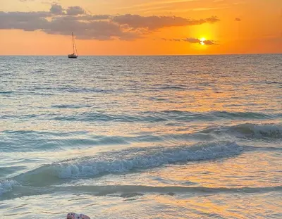 a boat in the ocean with a sunset in the background at Villa Elegante y Familiar en Pedernales, Cerca de la Playa del pueblo, Residencial SFA in Pedernales