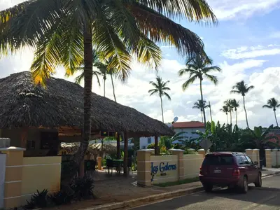 a car parked in front of a building with palm trees at Las Galeras Hotel in Las Galeras