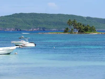 a boat sitting in the water next to an island at Las Galeras Hotel in Las Galeras