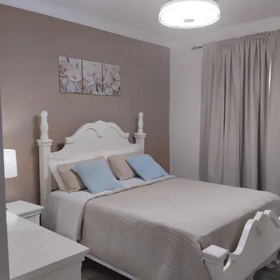 a white bedroom with a white bed with blue pillows at Nely y Pietro share apartment in Punta Cana